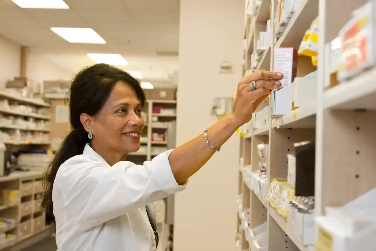 Farmacéutica tomando medicamentos de la estantería